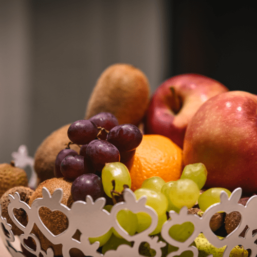 Obstkorb mit Weintrauben, Äpfeln, Orange und Kiwis